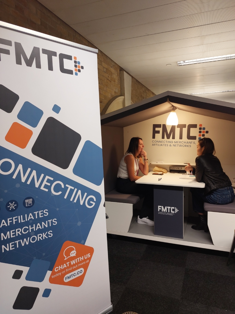 Two women sitting in a Nook booth with a banner in front.